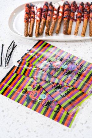 Téléchargez les photos : Emballage Halloween tiges de bretzel recouvertes de chocolat avec des aspersions dans des sacs-cadeaux. - en image libre de droit