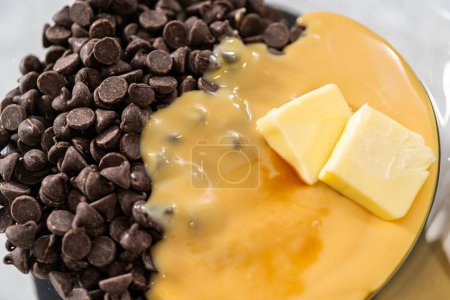 Photo for Melting white chocolate chips and other ingredients in a glass mixing bowl over boiling water to prepare candy cane fudge. - Royalty Free Image