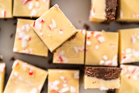 Téléchargez les photos : Couper le caramel à la canne à sucre avec un grand couteau de cuisine en morceaux carrés sur une planche à découper blanche. - en image libre de droit