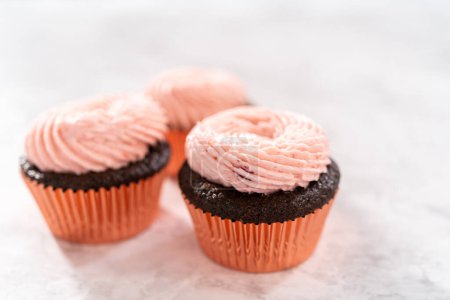 Téléchargez les photos : Cupcakes au chocolat givré avec glaçage à la crème au beurre aux fraises. - en image libre de droit