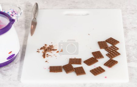 Téléchargez les photos : Enlever les mini chocolats du moule de chocolat en silicone dans une planche à découper blanche. - en image libre de droit