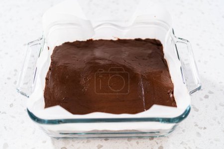 Téléchargez les photos : Verser le mélange de caramel dans le moule à pâtisserie tapissé de papier parchemin pour préparer le caramel nature. - en image libre de droit