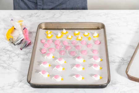 Photo for Piping meringue with piping bags into the baking sheet lined with parchment paper to bake Easter meringue cookies. - Royalty Free Image