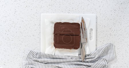 Téléchargez les photos : Flat lay. Cutting plain homemade fudge into small pieces on a white cutting board. - en image libre de droit