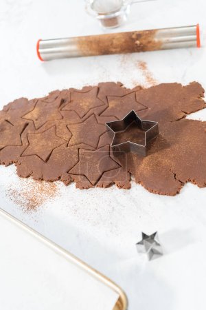 Photo for Cutting star-shaped chocolate graham crackers from the dough with a cookie cutter. - Royalty Free Image