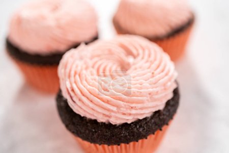 Foto de Cupcakes de chocolate esmerilados con glaseado de crema de mantequilla de fresa. - Imagen libre de derechos
