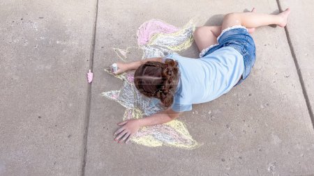 Photo for Little girl drawing chalk art on a suburban driveway on a summer day. - Royalty Free Image