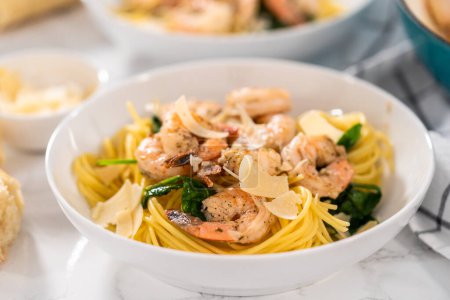 Téléchargez les photos : Servir des pâtes aux crevettes à l'ail avec des épinards dans des bols en céramique blanche. - en image libre de droit