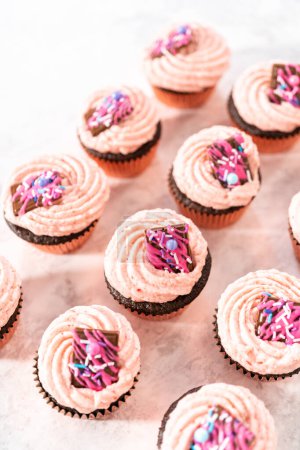 Téléchargez les photos : Cupcakes fraises au chocolat fraîchement cuits garnis de mini chocolats roses gourmands. - en image libre de droit