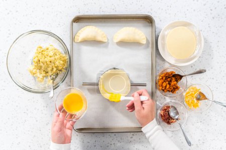Téléchargez les photos : Pose plate. Remplir la pâte empanada avec du remplissage d'œufs pour faire des empanadas petit déjeuner avec des œufs et des patates douces. - en image libre de droit