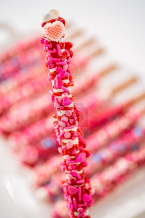 Schokoladenüberzogene Brezelstangen mit herzförmigen Streuseln zum Valentinstag.