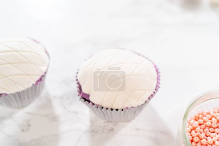 Téléchargez les photos : Décoration artistique des cupcakes à la vanille et au chocolat avec de délicates pièces fondantes les transforme en friandises festives adaptées à une célébration d'anniversaire. - en image libre de droit