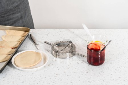 Foto de Relleno de masa de empanada con relleno de pastel de cereza para hacer empanadas de cereza dulce en la freidora. - Imagen libre de derechos
