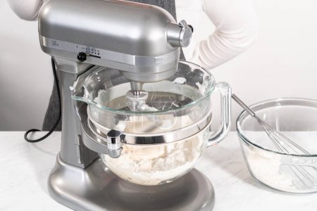 Téléchargez les photos : Mélange de pâte à pain dans un mélangeur de cuisine autonome pour cuire des torsions patriotiques à la cannelle. - en image libre de droit