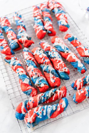 Photo for Drizzling white glaze on top of patriotic cinnamon twists. and decorating with star sprinkles. - Royalty Free Image