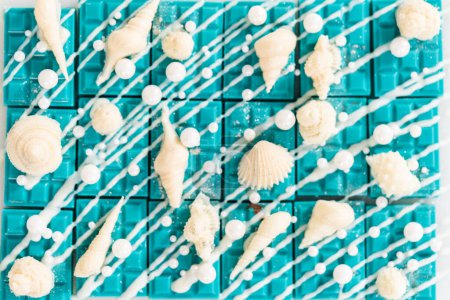 Foto de Mini barras de chocolate sirena rociado con chocolate blanco, espolvoreado con chispas de azúcar blanco perla, y decorado con conchas de chocolate blanco. - Imagen libre de derechos