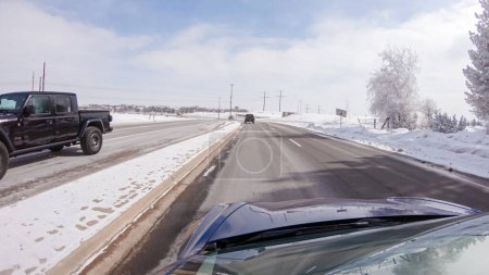 Foto de Castle Pines, Colorado, Estados Unidos-30 de enero de 2023-Tormenta post-invierno, el viaje en coche por una carretera suburbana ofrece un viaje tranquilo. La pintoresca escena, con nieve adornando el paisaje, se suma a la - Imagen libre de derechos