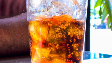 Photo for A close-up shot showcases a refreshing glass filled with ice cubes and soda pop, placed on a restaurant table, inviting the viewer to enjoy a cool and fizzy beverage. - Royalty Free Image