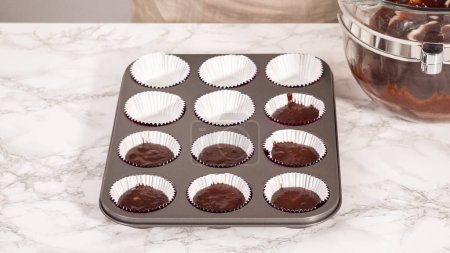 Foto de Step by step. Baking chocolate cupcakes. Scooping chocolate cupcake batter into a cupcake pan. - Imagen libre de derechos