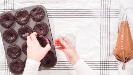 Téléchargez les photos : Pose plate. Pas à pas. Piping chocolat ganache glaçage sur le dessus de cupcakes au chocolat. - en image libre de droit