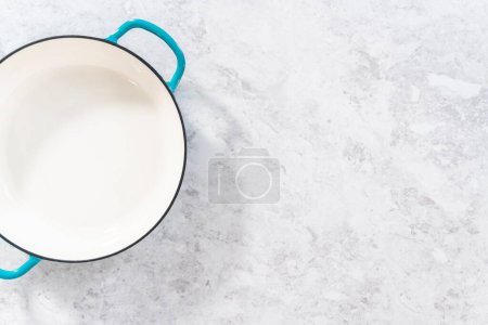 Téléchargez les photos : Braiser émaillé en fonte propre sur le comptoir de la cuisine. - en image libre de droit