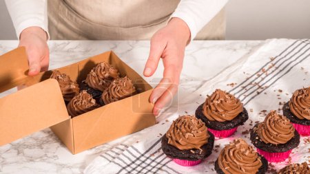 Téléchargez les photos : Pas à pas. Emballage de cupcakes au chocolat avec glaçage ganache au chocolat dans une boîte à cupcakes en papier. - en image libre de droit