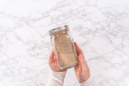Photo for Flat lay. Dry yeast in a glass mason jar on the marble surface - Royalty Free Image