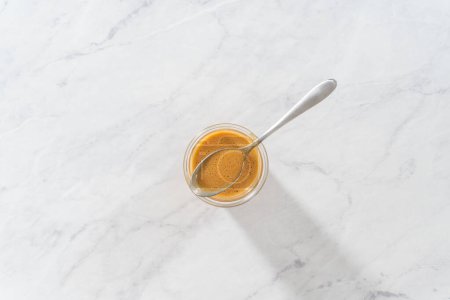 Photo for Flat lay. Caramel filling for bundt cake in a glass jar on the kitchen counter. - Royalty Free Image