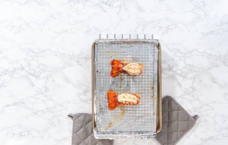 Téléchargez les photos : Pose plate. Beurrer les queues de homard sur une plaque de cuisson avec du papier d'aluminium de cuisine. - en image libre de droit