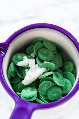 Photo for Melting green chocolate chips in a candy melting pot to make cactus cake pops for the Cinco de Mayo celebration. - Royalty Free Image