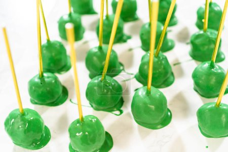 Téléchargez les photos : Tremper des boules de pâte dans du chocolat fondu vert pour faire éclater le gâteau au cactus pour la célébration du Cinco de Mayo. - en image libre de droit