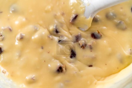 Photo for Melting white chocolate chips and other ingredients in a glass mixing bowl over boiling water to prepare white chocolate cranberry pecan fudge. - Royalty Free Image