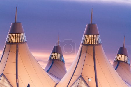 Photo for Glowing tents of DIA at sunrise. Denver International Airport well known for peaked roof. Design of roof is reflecting snow-capped mountains. - Royalty Free Image