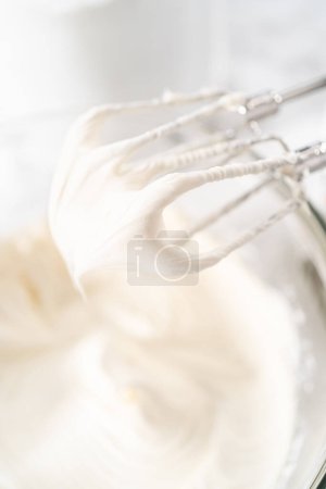 Téléchargez les photos : Mélange dans un bol de mélange en verre de glaçage à la crème au beurre acheté en magasin. - en image libre de droit
