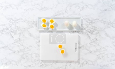 Téléchargez les photos : Trancher des œufs durs sur une planche à découper blanche. - en image libre de droit
