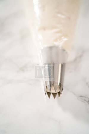 Photo for Peppermint buttercream frosting in a piping bag with a jumbo metal piping tip. - Royalty Free Image