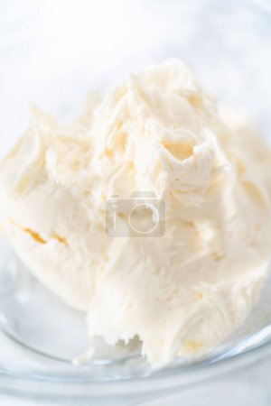 Photo for Mixing store-bought vanilla frosting in a mixing glass bowl with a hand mixer. - Royalty Free Image