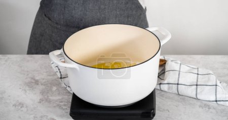 Téléchargez les photos : Sauter les légumes dans un four hollandais en fonte émaillée pour faire cuire la soupe aux pois cassés. - en image libre de droit