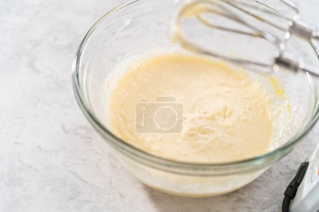 Photo for Mixing ingredients with a hand mixer in a large mixing bowl to make the cream cheese filling for carrot bundt cake. - Royalty Free Image