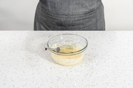 Téléchargez les photos : Mélange d'ingrédients humides dans un petit bol à mélanger en verre pour cuire des cupcakes dulce de leche. - en image libre de droit
