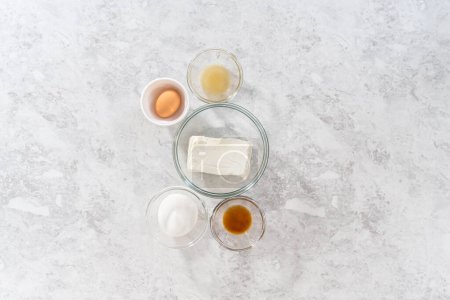 Téléchargez les photos : Pose plate. Ingrédients mesurés dans des bols à mélanger en verre pour faire le remplissage de fromage à la crème. - en image libre de droit