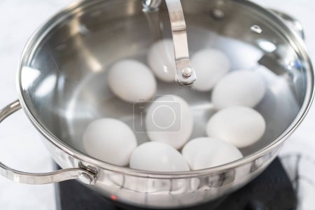 Foto de Huevos blancos hirviendo en una olla para preparar huevos duros. - Imagen libre de derechos