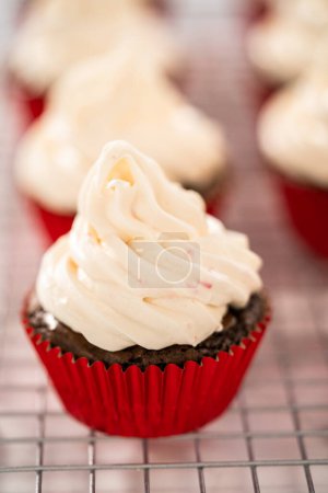 Téléchargez les photos : Glaçage à la crème au beurre à la menthe poivrée sur le dessus des cupcakes au chocolat et décoration avec des bonbons de canne à sucre à la menthe poivrée écrasée. - en image libre de droit