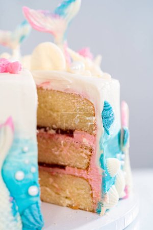 Photo for Slicing mermaid-themed 3 layer vanilla cake on a cake stand. - Royalty Free Image