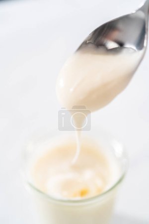 Téléchargez les photos : Glaçure au fromage à la crème dans un petit pot en verre. - en image libre de droit