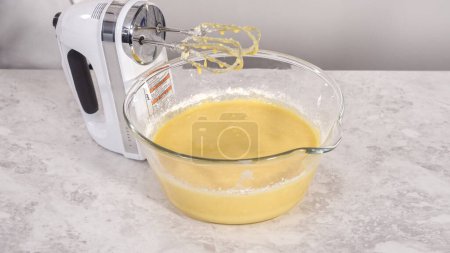 Photo for Step by step. Mixing ingredients in a glass mixing bowl to bake funfettti bundt cake. - Royalty Free Image