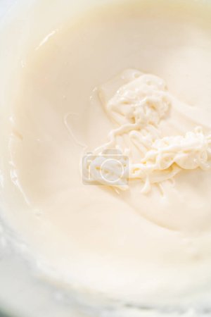 Foto de Mezclar los ingredientes en un tazón de vidrio grande para hacer el glaseado de queso crema. - Imagen libre de derechos