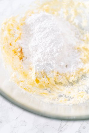Photo for Mixing ingredients in a large glass mixing bowl to prepare cream cheese drizzle sauce. - Royalty Free Image