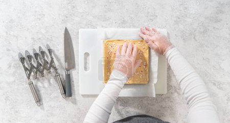 Foto de Flat lay. Removing candy cane fudge from a square cheesecake pan lined with parchment. - Imagen libre de derechos