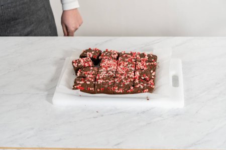 Cutting freshly baked peppermint brownies with chocolate peppermint chips into squares.